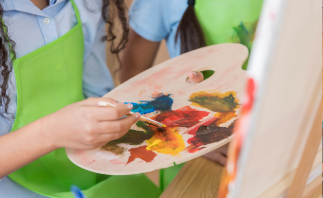 Student with paint, paint brush and easel